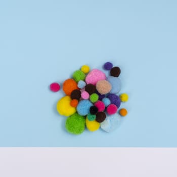 some felt balls  of various colors on a colored surface