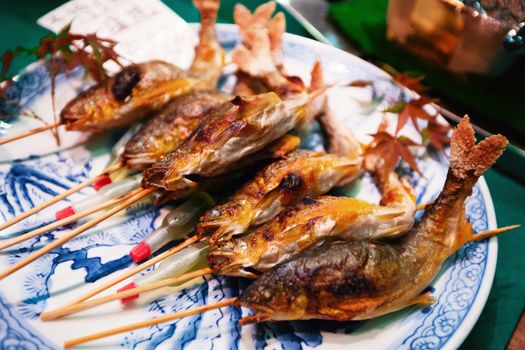 Grilled fishes on sticks as street food at Nishiki market in Kyoto, Japan.