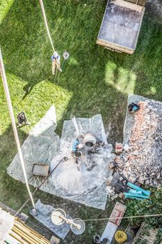 Top view of authentic builder men working with shovel during concrete cement solution mortar preparation in mixer at construction site.