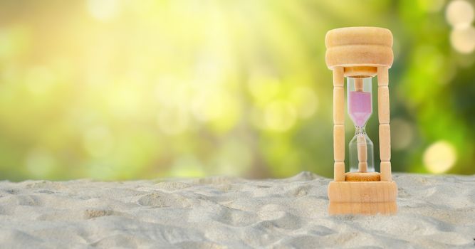 Hourglass set on a white sand background, natural green background, time concept