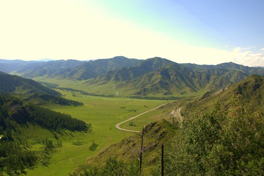 View from the top of the mountain on the road crossing a picturesque valley. Chike-Taman pass, Altai, Siberia, Russia.