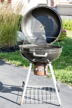 Black metal barbecue grill for cooking meat on coals, standing on legs with wheels