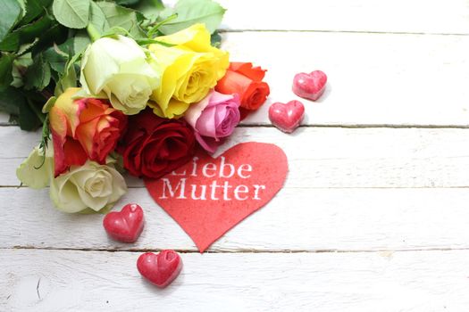 The picture shows colorful decoration with roses and a red heart with the german text dear mother.