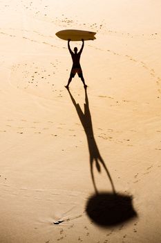 Top view of a surfer on the beach holding a surfboard