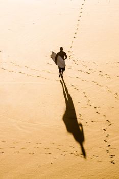 Top view of a surfer running on the beach