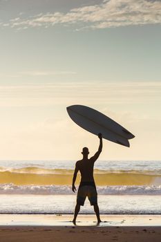 Surfer on the beach rising is surfboerd