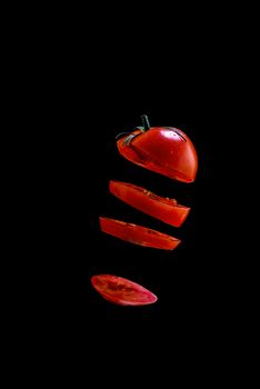 5 Flying red tomato slices on a black background