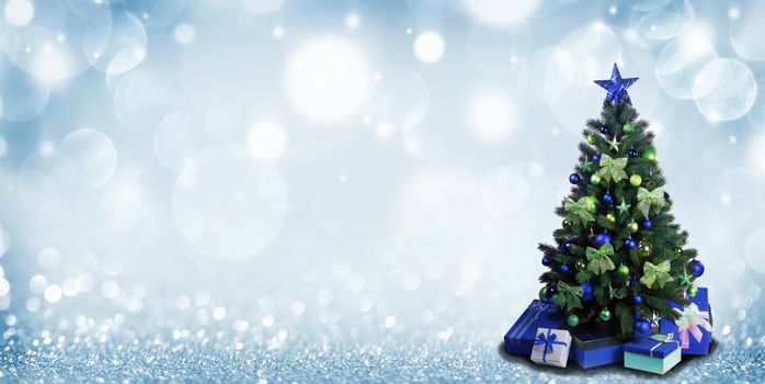 Fully decorated christmas tree with blue and green baubles and bows and presents on glitter bokeh background