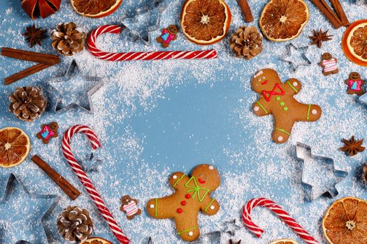 Christmas food frame. Gingerbread cookies, spices and decorations on blue background with copy space