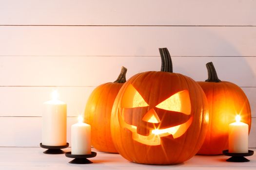 Halloween pumpkin head jack o lantern and candles on wooden background