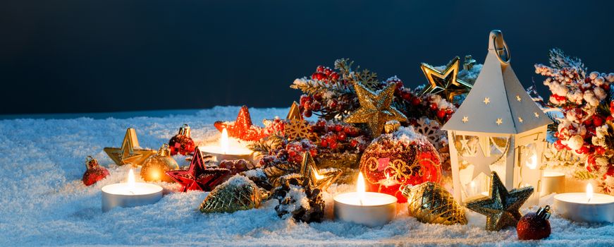 Burning candles , lantern and christmas decoration on snow
