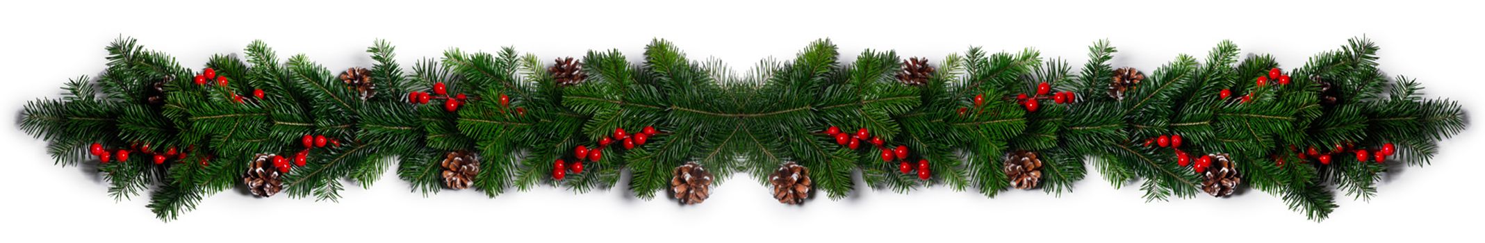 Christmas Border frame of tree branches red berries and pine cones on white background with copy space isolated