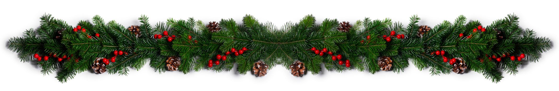 Christmas Border frame of tree branches red berries and pine cones on white background with copy space isolated