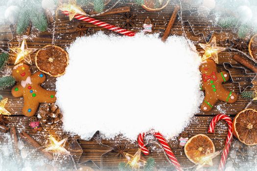Christmas food frame. Gingerbread cookies, spices and decorations on wooden background with copy space on snow