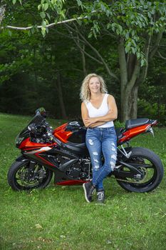young blond woman, leaning against her sport motocycle