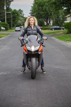 twenty something woman, sitting a on sport motocycle, in the middle of a rural street