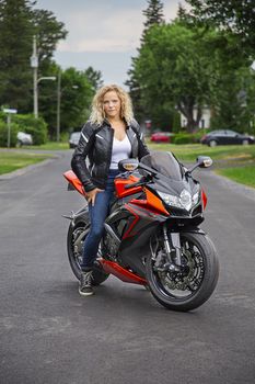 young woman, sitting on a sport motocycle, in a suburb street