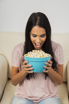 Young woman with mouth wide open over a blue bolw filled with popcorn