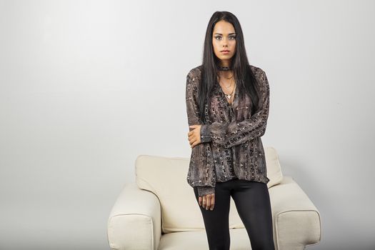 twenty something woman, wearing stylish clothes, standing in front of a white couch