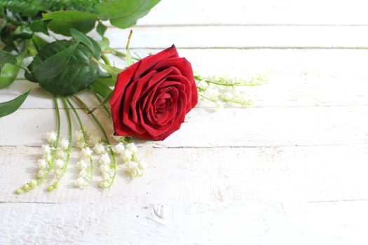 The picture shows a red rose and lily of the valley.