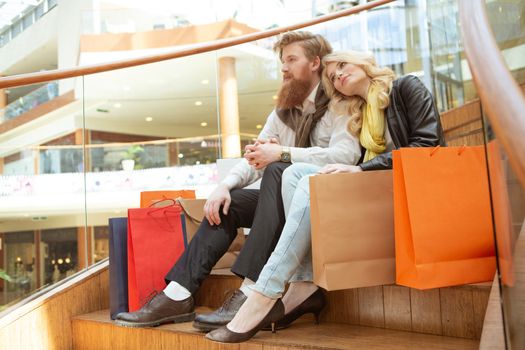 Happy beautiful young couple with shopping bags in mall