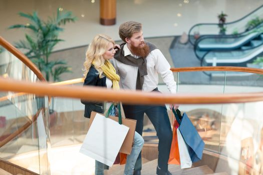 Happy beautiful young couple with shopping bags in mall