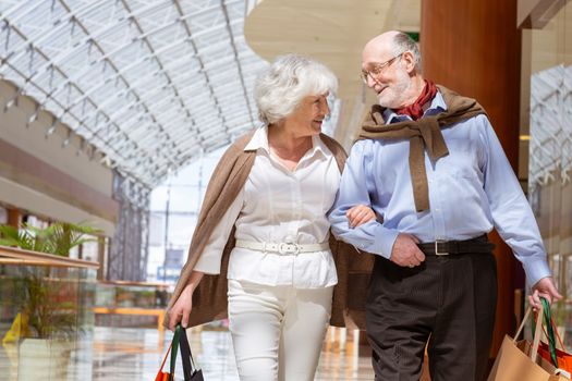 Adult senior couple with purchases in bags at shopping mall