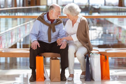 Adult senior couple with purchases in bags at shopping mall