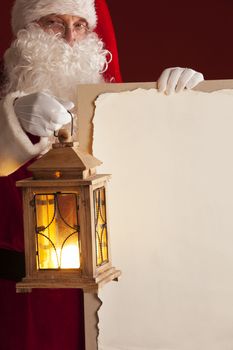 Santa Claus with lantern holding vintage paper billboard with copy space for text