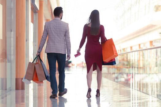 Happy beautiful young couple walking in mall holding shopping bags