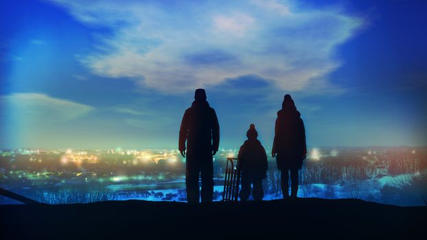 Family standing on a hill look at the evening lights of the Christmas city.