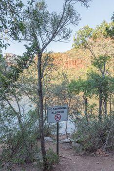 A no swimming sign on the peninsula hiking trail in the Blyde River Canyon. The Blyderivierspoort Dam is visible