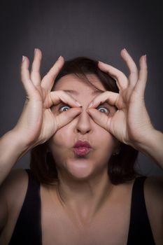 Woman grimaces in front of camera on black background