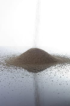 Pile of sand on a white reflective surface
