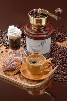 Coffee mill, cup and sweet on a glass