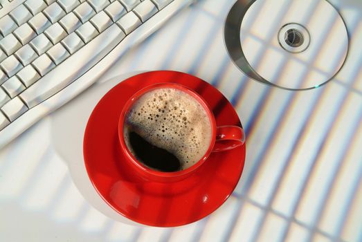 Cup of coffee, DCs and keyboard on a studio background