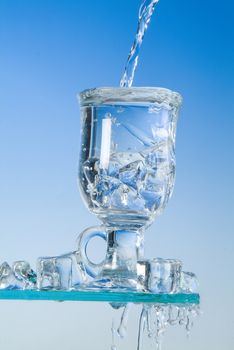 Glass and pouring water on a blue backround