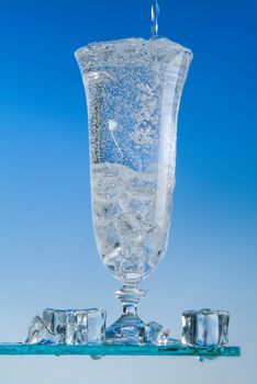 Glass and pouring water on a blue backround
