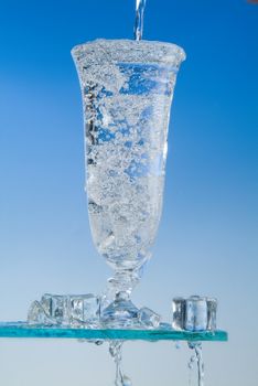 Glass and pouring water on a blue backround