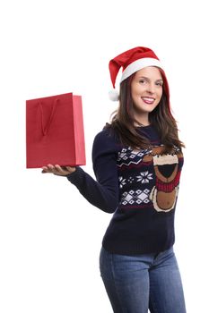 A portrait of a beautiful smiling young girl in winter clothes wearing Santa's hat, holding a shopping a bag, isolated on white background.