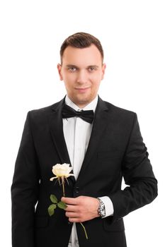 A portrait of a smiling handsome young man in a suit holding a flower, isolated on white background.