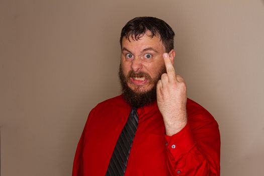 Bearded man holding his hand up raising the middle finger while making a mad expression on his face