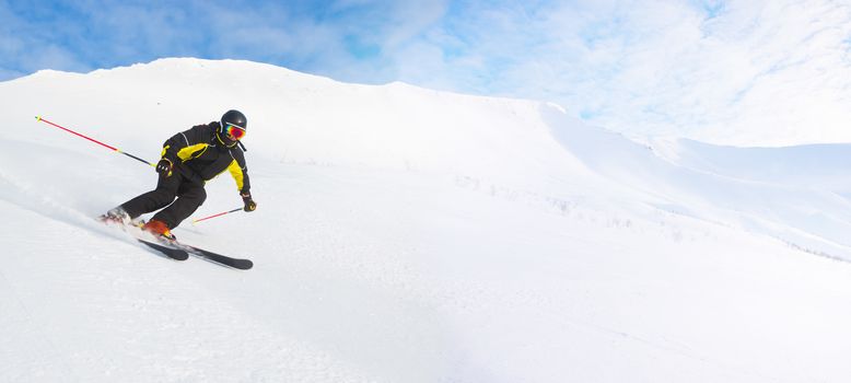 Skier in high mountains skiing downhill on piste copy space for text