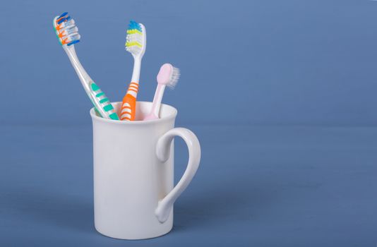 Toothbrushes in a cup on a blue wooden table