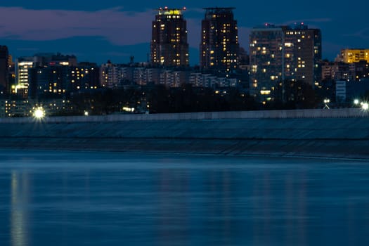 Night View of the city of Khabarovsk from the Amur river. Blue night sky. The night city is brightly lit with lanterns.