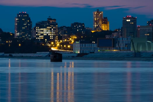 Night View of the city of Khabarovsk from the Amur river. Blue night sky. The night city is brightly lit with lanterns.