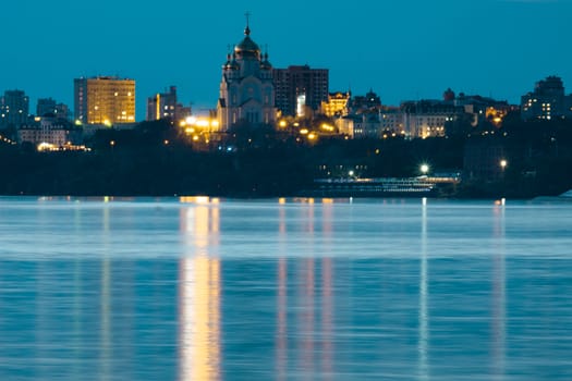 Night View of the city of Khabarovsk from the Amur river. Blue night sky. The night city is brightly lit with lanterns.