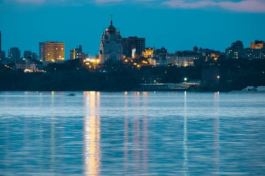 Night View of the city of Khabarovsk from the Amur river. Blue night sky. The night city is brightly lit with lanterns.