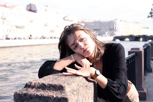 Beautiful young woman on embankment near river in city