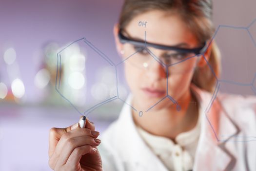 Portrait of a confident female health care expert in life science laboratory writing structural chemical formula on a glass board. Healthcare and modern life science concept. Blue toned image.